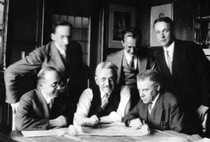 В центре сидят Альберт Кан; в центре стоит Мориц Кан; слева сидят Эйб Л. Драбкин В центре сидят Альберт Кан; в центре стоит Мориц Кан; слева сидят Эйб Л. Драбкин